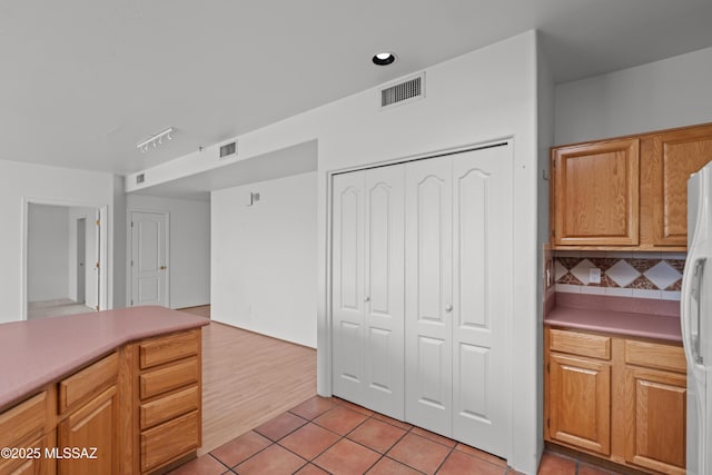 kitchen featuring decorative backsplash, light tile patterned floors, white fridge with ice dispenser, and visible vents