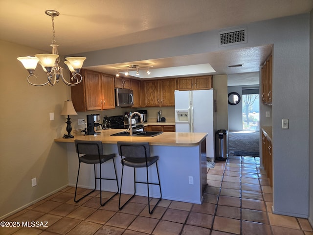 kitchen with visible vents, light countertops, a peninsula, stainless steel microwave, and white refrigerator with ice dispenser
