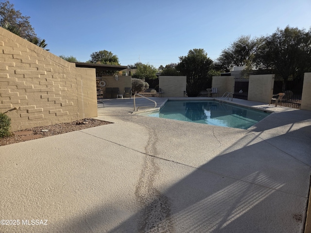 community pool with a patio and fence