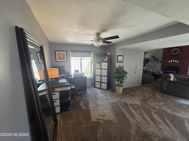 office area featuring a large fireplace, a ceiling fan, and carpet flooring