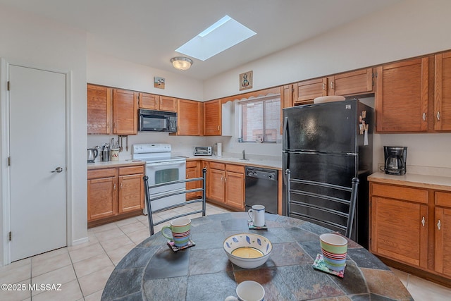 3055 S Placita De La Picaza, Green Valley, AZ 85622 - kitchen with black appliances, a skylight, lofted ceiling, light tile patterned floors, and brown cabinets