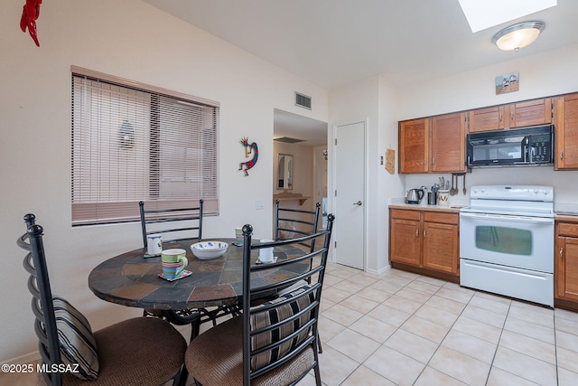 3055 S Placita De La Picaza, Green Valley, AZ 85622 - kitchen with black microwave, white range with electric stovetop, light countertops, brown cabinets, and a skylight