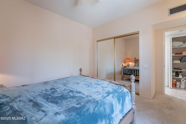 bedroom with a ceiling fan, light carpet, a closet, and visible vents