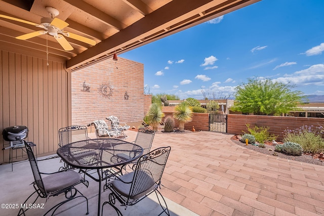 view of patio / terrace featuring a gate, fence, outdoor dining space, and a ceiling fan