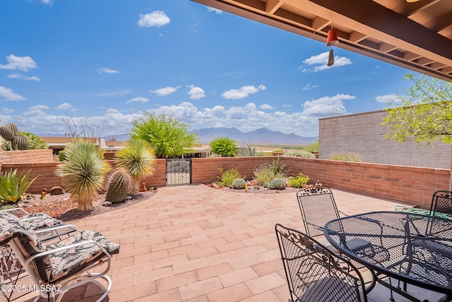 view of patio / terrace with a mountain view, outdoor dining area, a gate, and fence private yard