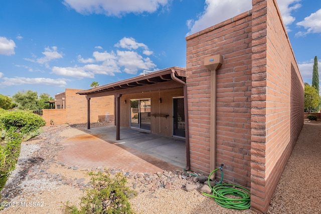 rear view of property with a patio area and brick siding