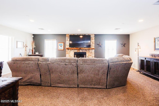 living room featuring visible vents, a stone fireplace, carpet, and recessed lighting