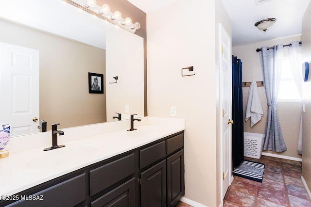 full bath with baseboards, a sink, and double vanity
