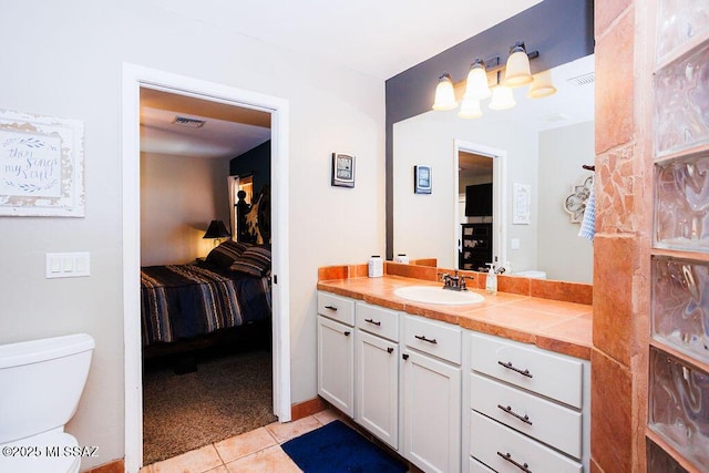 ensuite bathroom featuring connected bathroom, vanity, toilet, tile patterned flooring, and visible vents