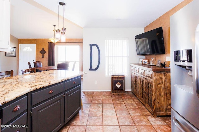 kitchen featuring stainless steel fridge with ice dispenser, light stone countertops, hanging light fixtures, and baseboards