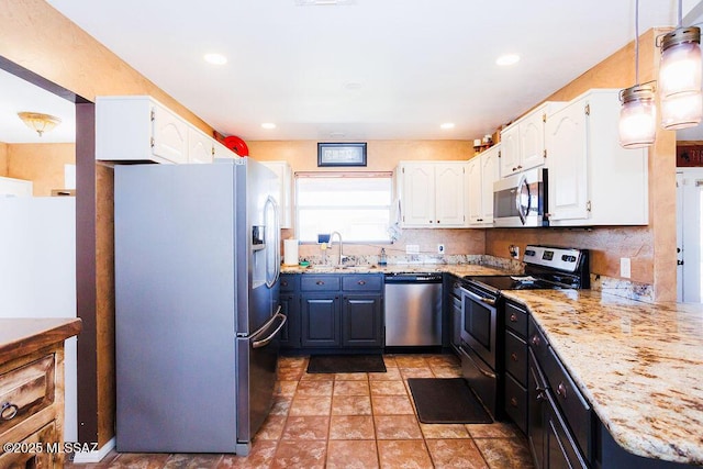 kitchen with white cabinets, stainless steel appliances, a sink, and light stone counters