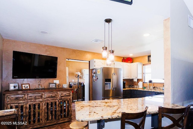 kitchen featuring white cabinets, a breakfast bar, light stone countertops, a peninsula, and stainless steel refrigerator with ice dispenser