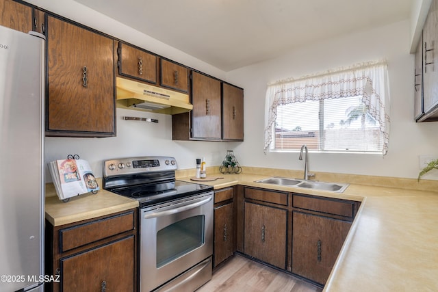 kitchen featuring light countertops, under cabinet range hood, a sink, and stainless steel appliances