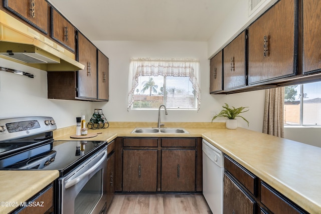 kitchen with light countertops, electric range, under cabinet range hood, white dishwasher, and a sink