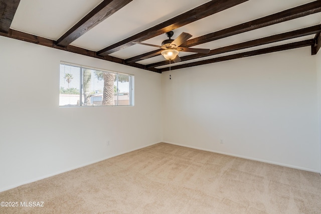 carpeted empty room with baseboards, beamed ceiling, and ceiling fan