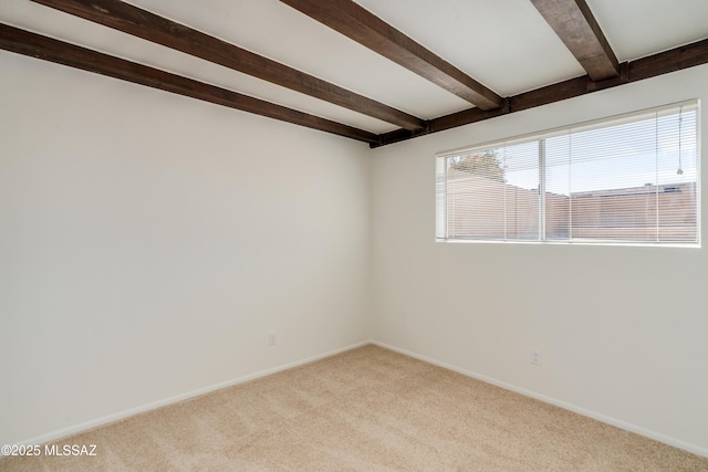 carpeted empty room with baseboards and beam ceiling