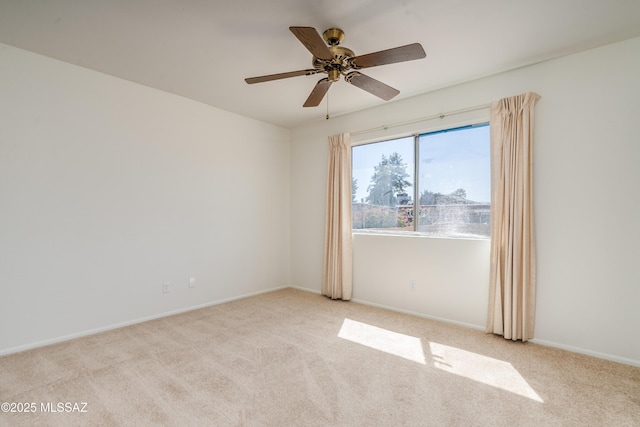carpeted spare room featuring baseboards and a ceiling fan