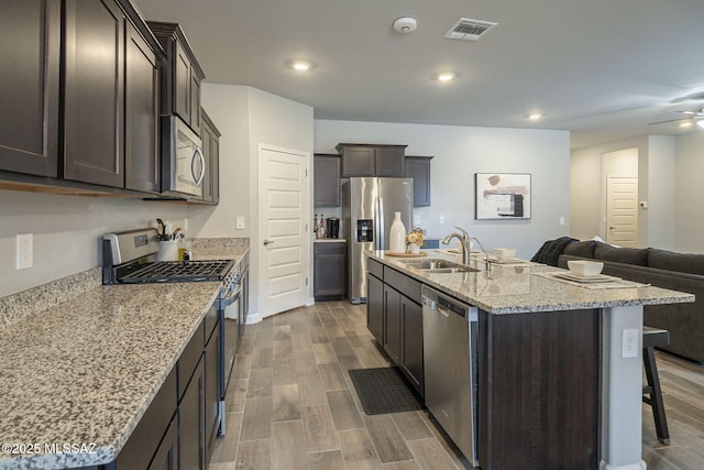 1117 W Valley Meadow Ln, Sahuarita, AZ 85629 - kitchen with appliances with stainless steel finishes, a sink, open floor plan, dark brown cabinets, and wood finished floors