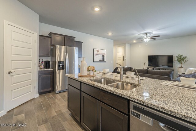 1117 W Valley Meadow Ln, Sahuarita, AZ 85629 - kitchen with appliances with stainless steel finishes, a sink, dark brown cabinetry, ceiling fan, and light stone counters