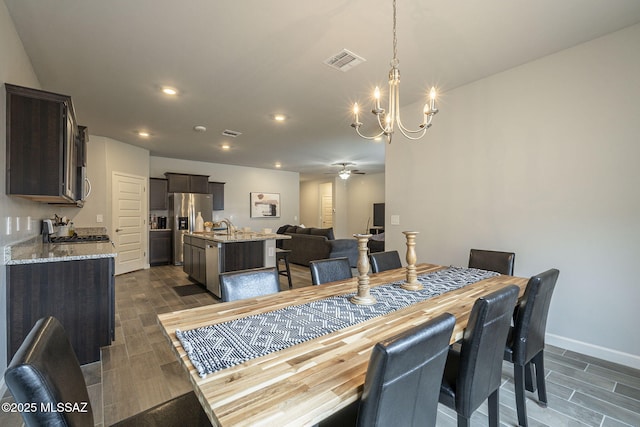 1117 W Valley Meadow Ln, Sahuarita, AZ 85629 - dining space featuring a chandelier, wood tiled floors, baseboards, a ceiling fan, and recessed lighting
