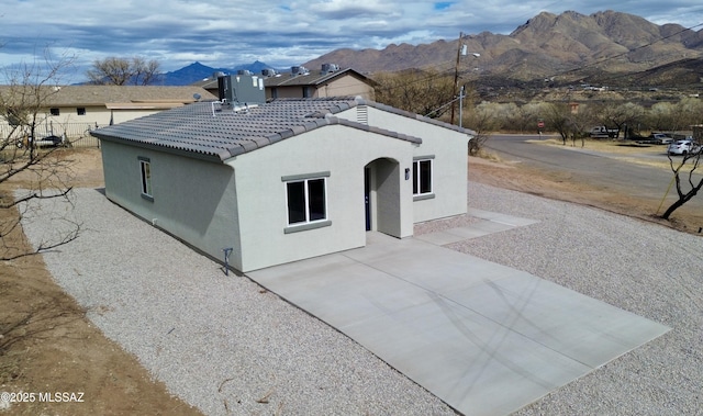 exterior space with a patio, a mountain view, stucco siding, and a tile roof