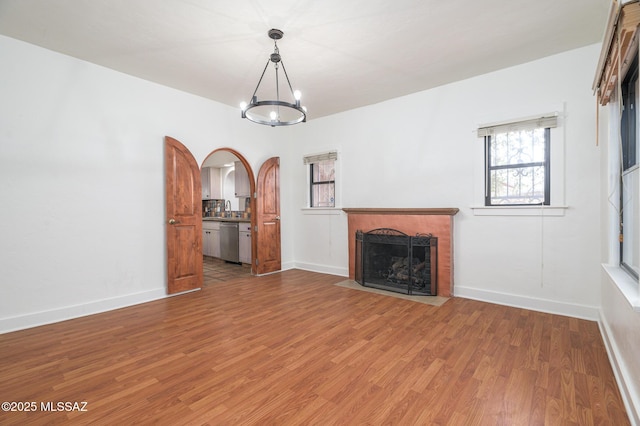3737 E Pima St, Tucson, AZ 85716 - unfurnished living room featuring a chandelier, wood finished floors, a fireplace, and baseboards