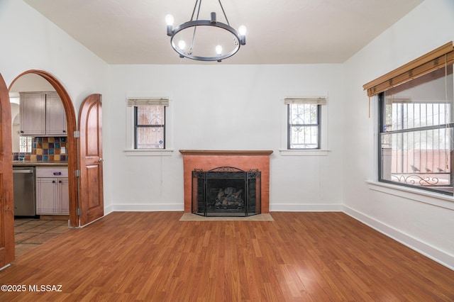 3737 E Pima St, Tucson, AZ 85716 - unfurnished living room with a brick fireplace, a notable chandelier, wood finished floors, and baseboards