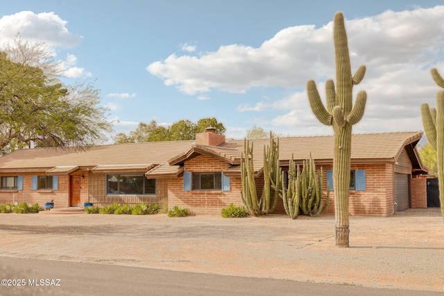 6341 E Brian Kent St, Tucson, AZ 85710 - view of front of property featuring a garage, brick siding, driveway, and a chimney