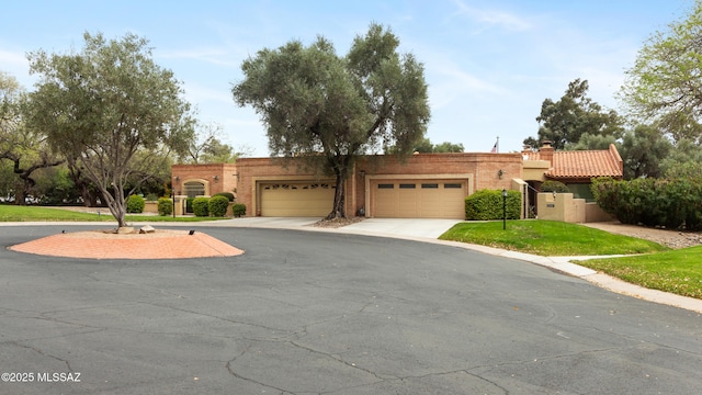 view of front of house with a chimney, driveway, a front yard, brick siding, and a garage