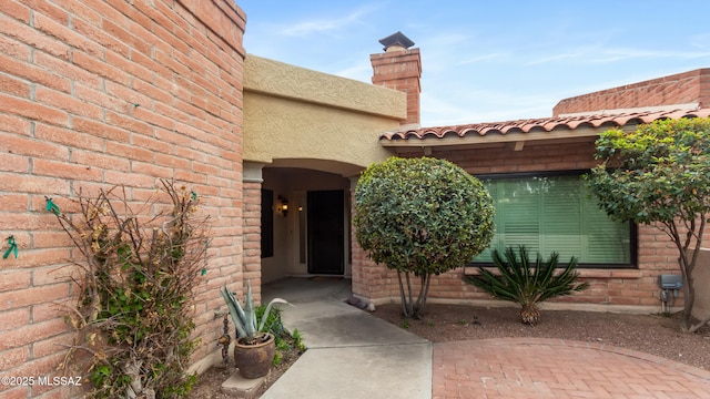 view of exterior entry with brick siding and stucco siding