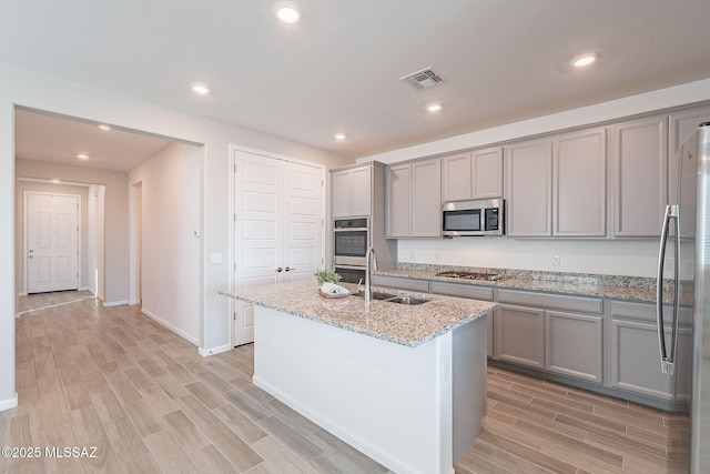kitchen with visible vents, gray cabinets, a sink, light wood finished floors, and appliances with stainless steel finishes