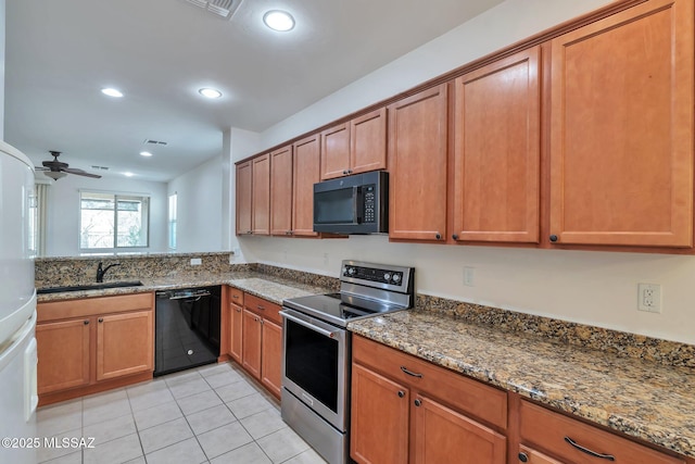 12171 N Golden Mirror Dr, Marana, AZ 85658 - kitchen featuring black appliances, a sink, brown cabinetry, light tile patterned floors, and stone countertops