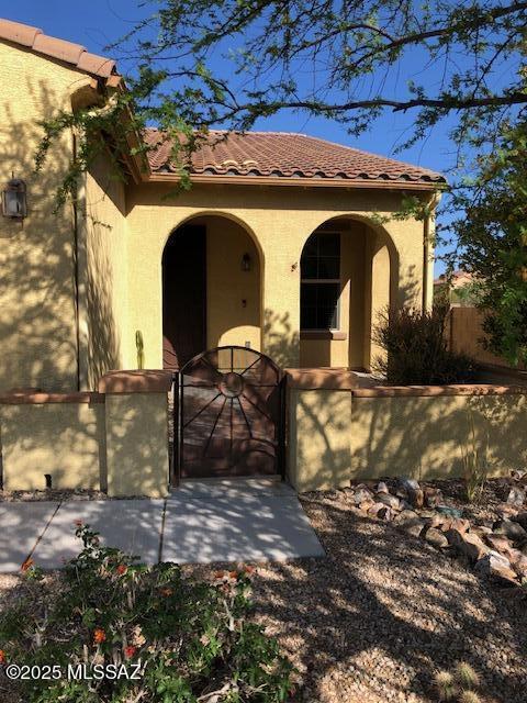 view of front of property with a gate, stucco siding, a tiled roof, and fence private yard