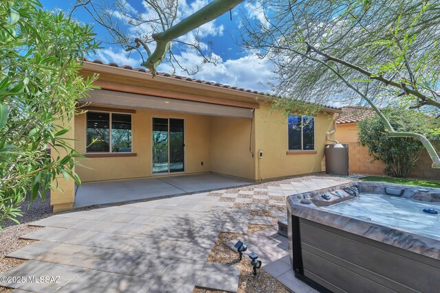 back of house featuring a patio, a tile roof, a hot tub, and stucco siding