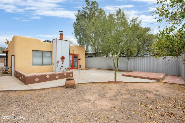 view of front facade featuring a patio, french doors, stucco siding, and fence