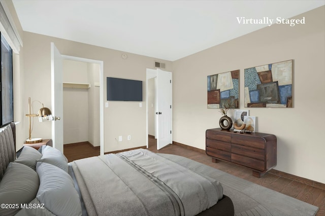 bedroom with baseboards, a closet, a spacious closet, visible vents, and wood finished floors