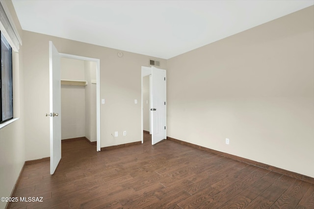 unfurnished bedroom featuring a closet, baseboards, dark wood-style floors, and visible vents