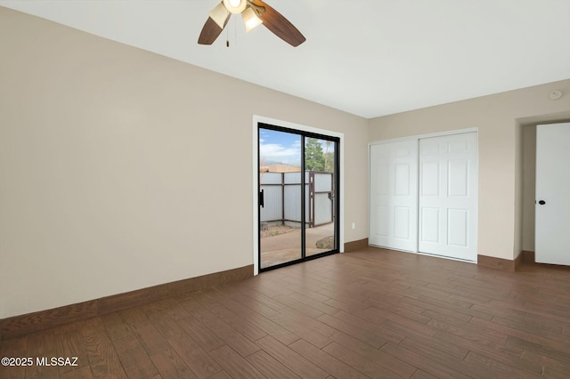 unfurnished bedroom featuring a closet, baseboards, access to outside, and dark wood-style floors