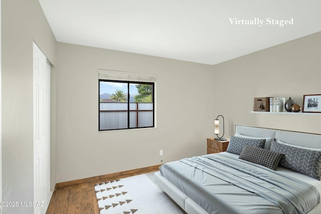 bedroom with a closet, baseboards, and wood finished floors