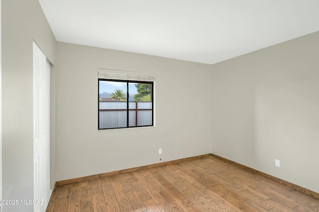 spare room featuring wood-type flooring and baseboards