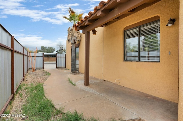view of home's exterior with fence, a patio, a gate, and stucco siding