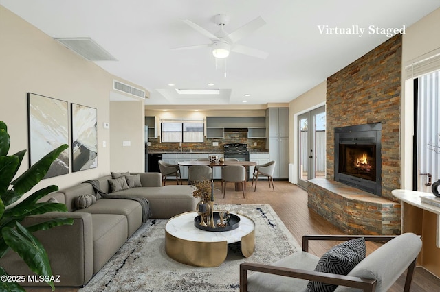 living area with visible vents, a stone fireplace, and wood finished floors