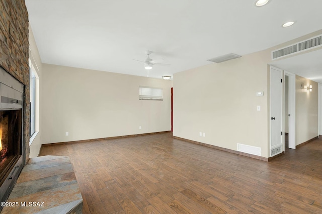 unfurnished living room featuring wood finished floors, a fireplace, a ceiling fan, and visible vents