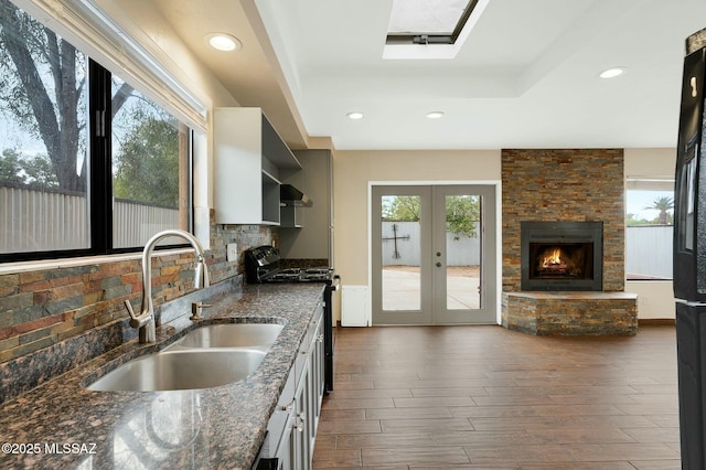 kitchen featuring dark wood-type flooring, dark stone countertops, a sink, black electric range oven, and french doors