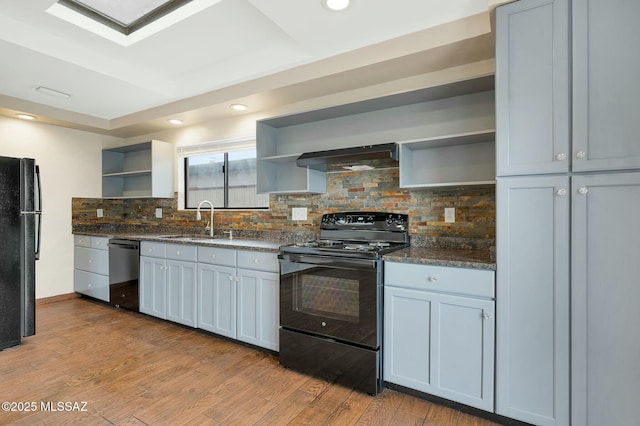kitchen featuring open shelves, a sink, under cabinet range hood, black appliances, and wood finished floors