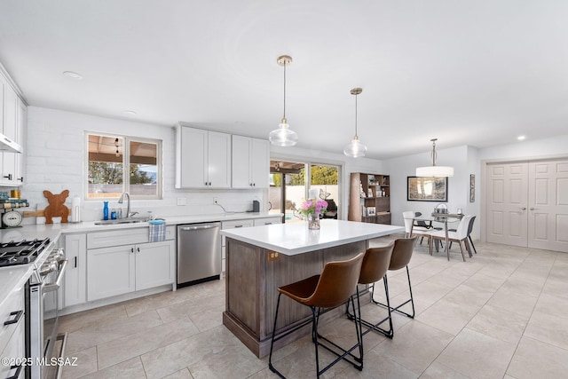 kitchen featuring stainless steel appliances, a wealth of natural light, a sink, and backsplash