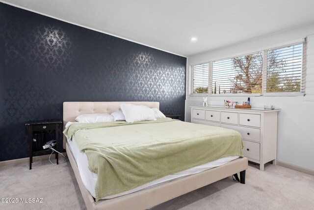 bedroom featuring light carpet, an accent wall, baseboards, and wallpapered walls