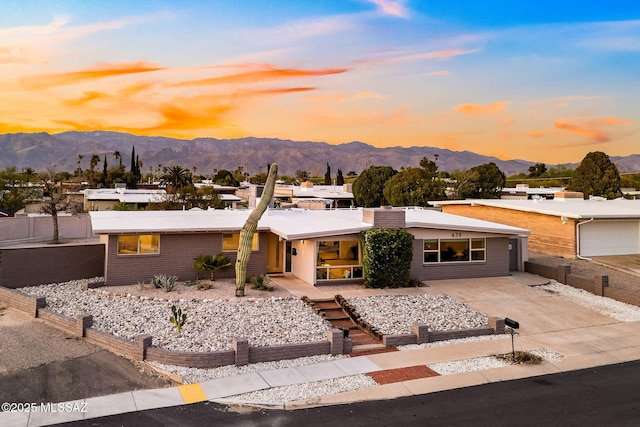 mid-century inspired home featuring a mountain view, fence, and concrete driveway