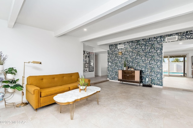 living area featuring an accent wall, beam ceiling, and visible vents