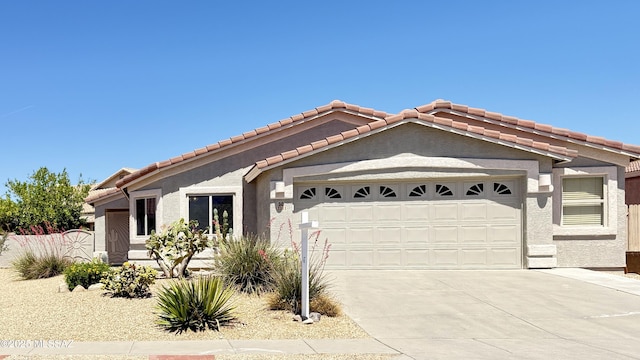 ranch-style house featuring an attached garage, fence, a tile roof, and stucco siding